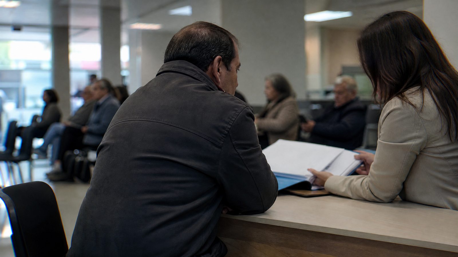Cliente ao balcão de uma agência bancária a falar com um gestor sobre o crédito à habitação.